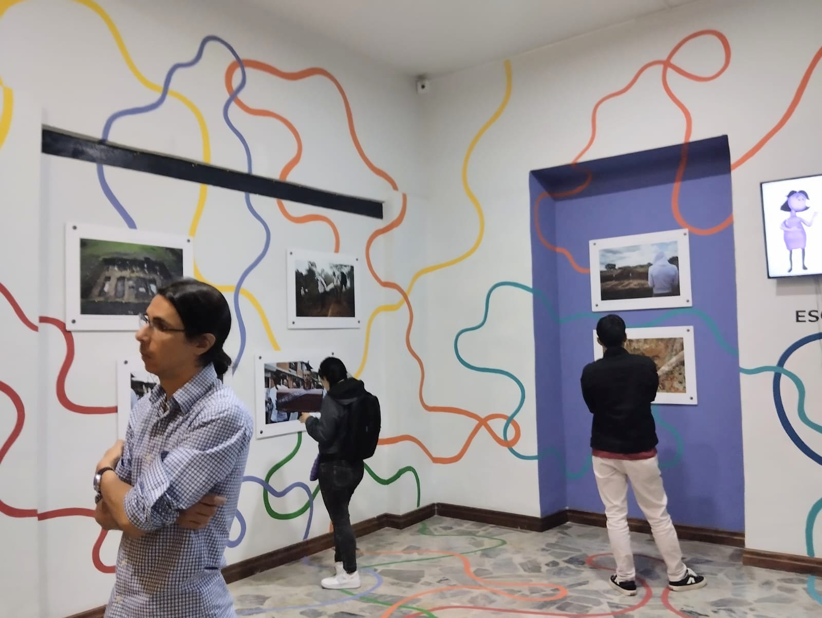 Personas viendo imágenes de la exposición El camino de la búsqueda en museo de Pasto