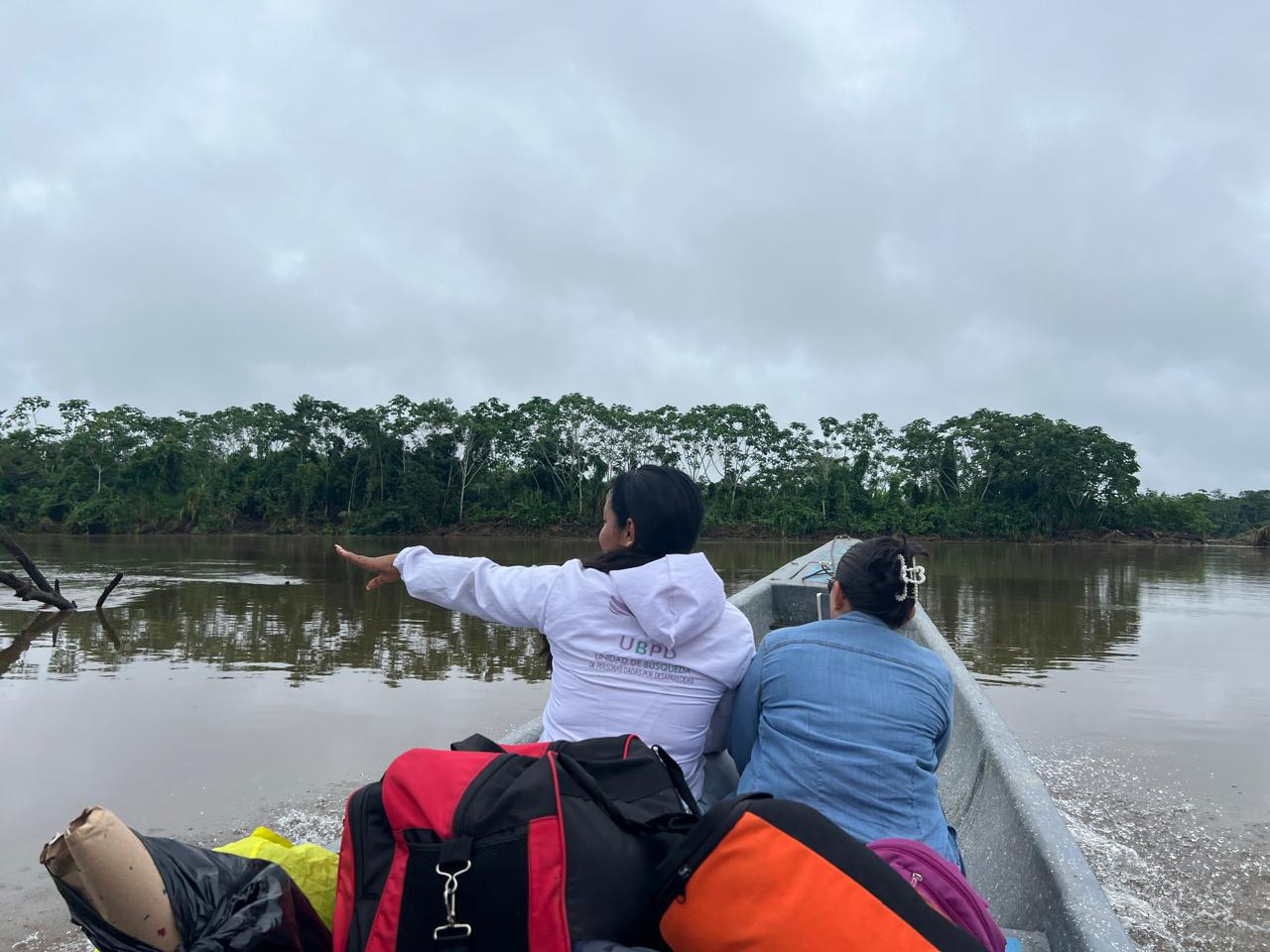 Funcionaria de la UBPD y mujer indígena sobre barco en un río de Putumayo