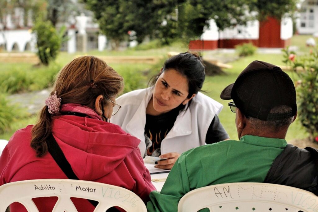 Una funcionaria de la UBPD atendiendo a dos familiares buscadores en el cemeterio municipal de Rionegro, en Antioquia.