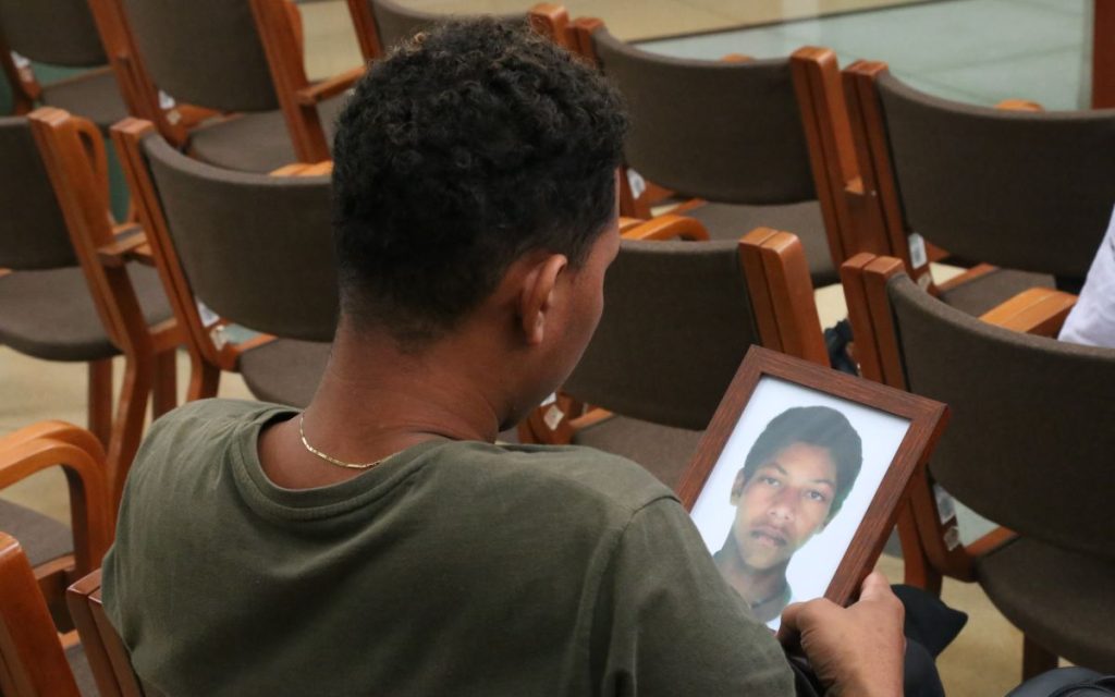 Parada junto al cofre donde reposa su hermano, quien estuvo desaparecido durante 23 años, Martha Isabel no deja de llorar. Cada tanto abre la caja de madera y toca las estructuras óseas que hay en el interior. Sus parientes se acercan y lloran junto a ella. Algunos la abrazan y otros miran la pintura de un cafetal en la que se ve a un muchacho moreno, de nariz achatada y cabello crespo recolectando granos de café. Ese joven es Juan Carlos Castaño Tobón, cuyo cuerpo fue entregado de manera digna por la Unidad de Búsqueda de Personas dadas por Desaparecidas (UBPD).