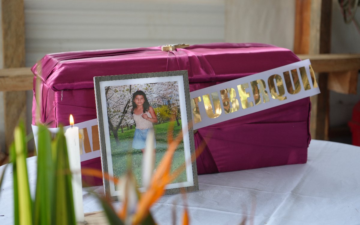 Un cofre fúnebre envuelto en tela rosada con una cinta blanca que dice 