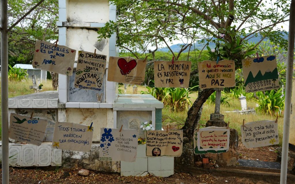 Carteles colgados con ganchos de ropa frente a las tumbas con los siguientes mensajes escritos a mano:

"Buscarles es un acto de amor"

"No descansar, no desfallecer hasta encontrarles"

"La memoria es resistencia y paz"

"Total admiración a quienes buscan. Aquí se hace paz"

"Todos y todas merecen ser buscados/as"

"La búsqueda por los desaparecidos continúa..."

"Una persona desaparecida duele hasta el último día de la última persona que alguna vez amo"

"Cuando la ausencia persiste, la dignidad no desaparece"

"Que esta ruta les grite al oído, ¡están presentes!"