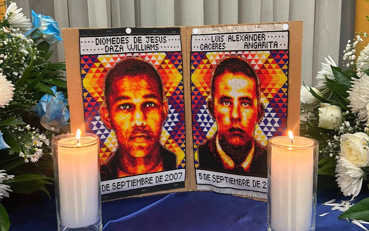 Dos retratos elaborados en tejido con cuentas de colores muestran los rostros de Diomedes de Jesús Daza Williams y Luis Alexander Cáceres Angarita. Cada imagen incluye sus nombres en la parte superior y la fecha de su desaparición o fallecimiento en la parte inferior. Al frente hay dos velas encendidas en vasos de vidrio y a los lados arreglos de flores blancas.
