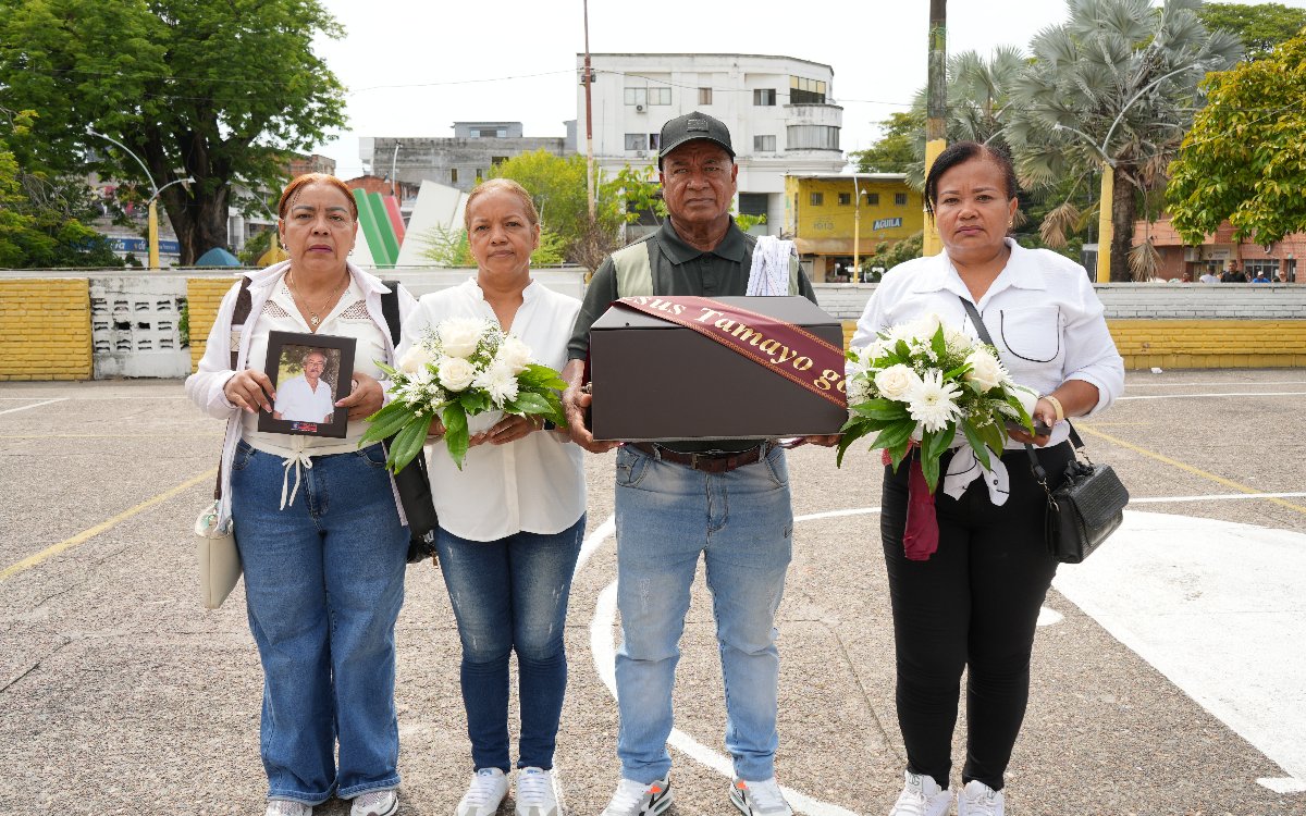 Cuatro personas sostienen un cofre fúnebre con la cinta 